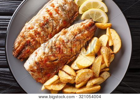 Grilled Mackerel Served With Potato Wedges And Lemon Closeup On A Plate. Horizontal Top View