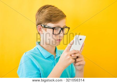 Handsome Boy In Glasses Plays Tablet. The Concept Of Poor Eyesight, Harm Of Gadgets, Myopia