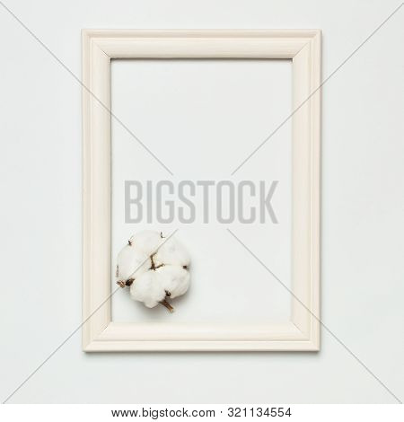 White Wooden Photo Frame And Cotton Flower On Gray Background. Flat Lay Top View Copy Space. Stylish