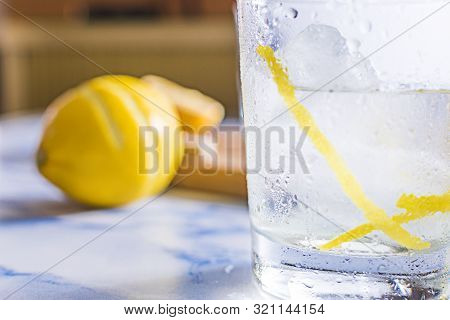 Gintonic Cocktail In A Glass With Ice And Lemon, With The Ingredients Aside.