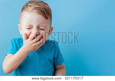 Ill Young Child With A Thermomether, Measuring The Height Of His Fever And Looking Into The Camera