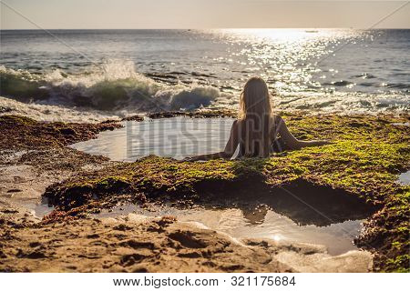 Young Woman Tourist On Pantai Tegal Wangi Beach Sitting In A Bath Of Sea Water, Bali Island, Indones
