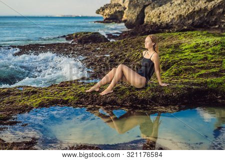 Young Woman Tourist On Pantai Tegal Wangi Beach Sitting In A Bath Of Sea Water, Bali Island, Indones