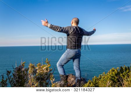 Bald Man On A Cliff Edge, Spread His Arms Against Sea View. Happy And Confident 

Man On The Cliff W