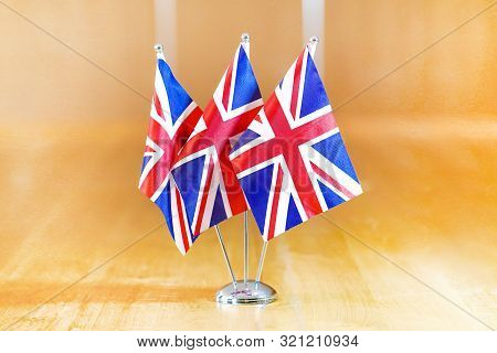 Three Flags On The Table. Flags Of United Kingdom. Flags Of United Kingdom On The Table During A Mee
