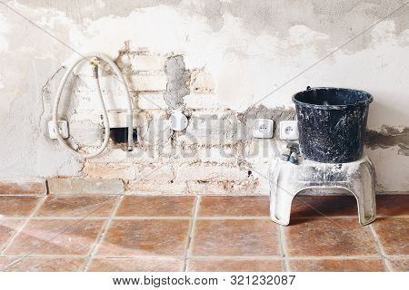 Black Dirty Bucket And Spatula Tools And White Brick Wall. Unfinished Room Reconstruction. Home Repa