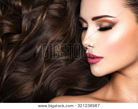 Beautiful woman with long bown hair. Portrait of an sensual adult girl with curly hair.