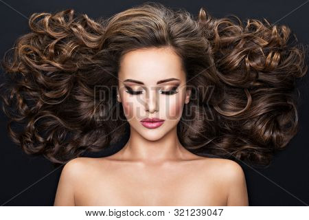 Beautiful woman with long bown hair. Portrait of an sensual adult girl with curly hair.