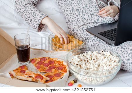 Unrecognized Woman Eating Unhealthy Food And Crying. Caucasian Teenage Girl In Cute Warm Pajamas Sit