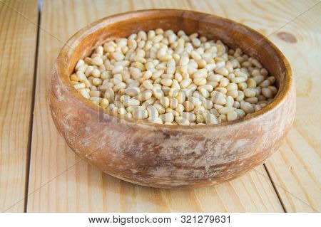 Close-up Of Peeled Pine Nuts In A Wooden Bowl, On A Light Wooden Background, Organic Food
