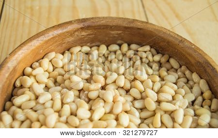 Close-up Of Half Wooden Bowl With Peeled Pine Nuts, Light Wood Background, Organic Food