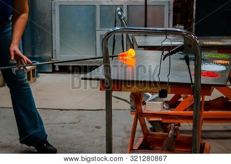 Rolling Out Molten Glass To Blow Into A Bowl