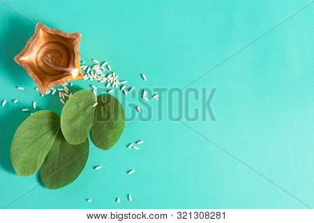 Happy Dussehra. Clay Diya Lamps Lit During Dussehra With Yellow Flowers, Green Leaf And Rice On Gree