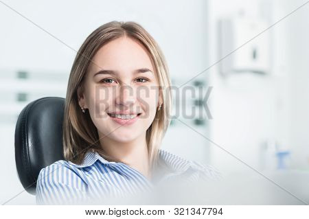 Portrait Of An Attractive Smiling Girl Blonde In A Dental Chair. Happy Customer Dental Cabinet