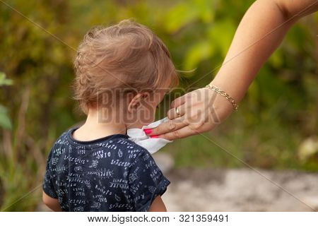 Hygiene - mom wiping the baby face skin with wet wipes. Cleaning wipe, pure, clean, outdoor