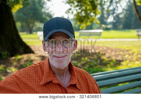 A Senior Man In Blue Baseball Cap And Orange Shirt, Portrait