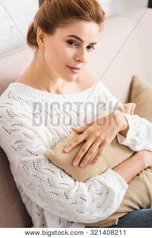 Attractive Woman In White Sweater Holding Pillow And Looking Away