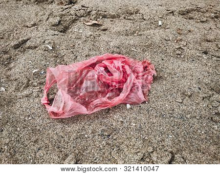 Single Use Plastic Bag In Sand Top View, Marine Trash On The Beach. Plastic Pollution On The Beach. 