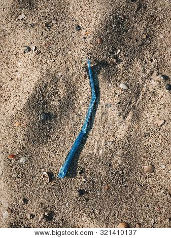 Plastic Pollution On The Beach. Single Use Plastic Straw In Sand, Marine Trash On The Beach. Stop Pl