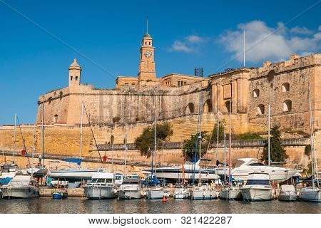Malta. Senglea Marina. White Yachts On Ancient Stone Wall Background. Senglea Cityscape.