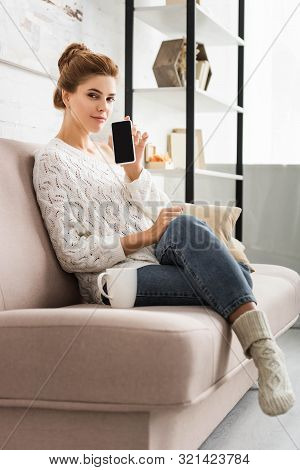 Attractive Woman In White Sweater Holding Smartphone With Copy Space