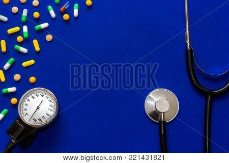 Medical Pills, Tonometer And Stethoscope On The Blue Surface. Blood Pressure Measurement. Color Caps