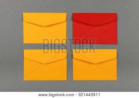 Four Unopen Yellow And Red Paper Mail Envelopes Over Grey Background, Flat Lay, Directly Above