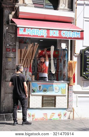 ISTANBUL, TURKEY - JUNE 7, 2019: Turkish ice cream vendor demonstrates the sticky chewy Turkish ice cream dondurma