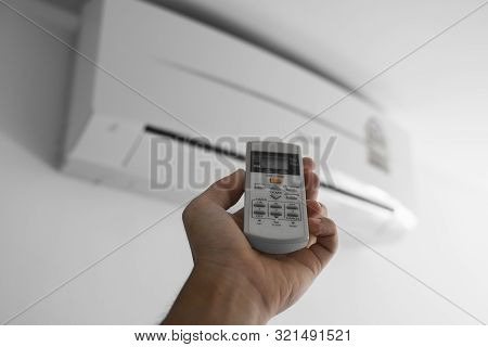 Mans Hand Using Remote Controler. Hand Holding Rc And Adjusting Temperature Of Air Conditioner Mount