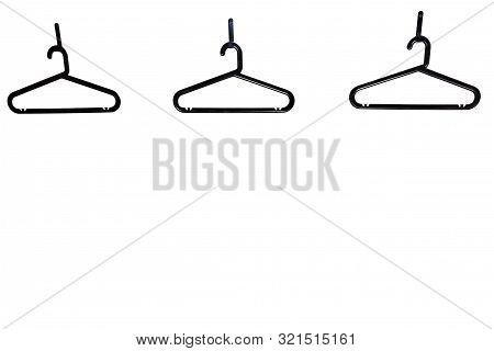 Three Black Plastic Coat Hangers With A Trouser Bar On White Isolated Background And Copy Space