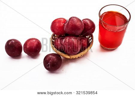 Raw Organic Red Ripe Plums In A Brown-colored Basket Along With Its Extracted Tincture Or Extracted