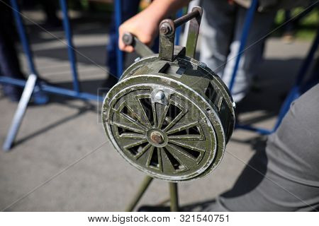 Shallow Depth Of Field Image With A Man Handling A Vintage Hand Crank Air Raid Siren
