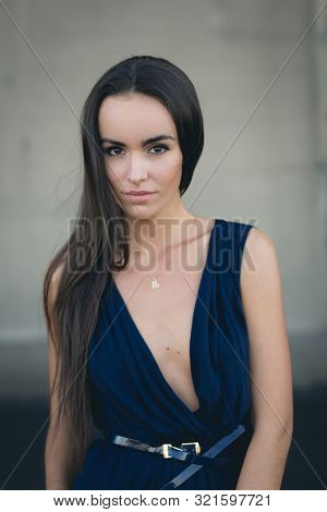 Closeup Portrait Of A Happy Young Brunette Teenage Girl Outdoor. Concrete Wall On Background