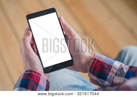 Mockup Image: Man Looking At Black Smartphone With White Blank Screen. Close Up View Of Man Hands Wi