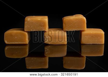 Group Of Five Whole Sweet Golden Caramel Candy Isolated On Black Glass