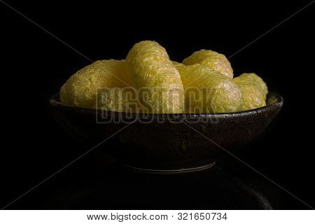 Lot Of Whole Salted Yellow Corn Puff In Dark Ceramic Bowl Isolated On Black Glass