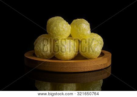 Group Of Five Whole Salted Yellow Corn Puff On Bamboo Coaster Isolated On Black Glass