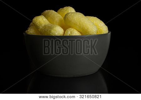 Lot Of Whole Salted Yellow Corn Puff In Gray Ceramic Bowl Isolated On Black Glass