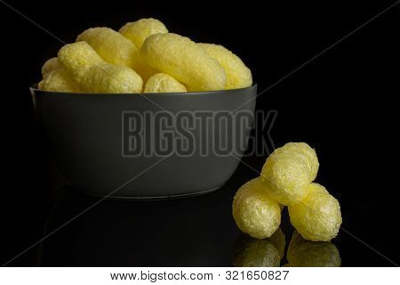 Lot Of Whole Salted Yellow Corn Puff In Gray Ceramic Bowl Isolated On Black Glass