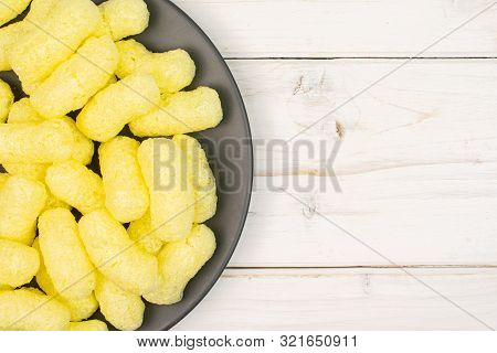 Lot Of Whole Salted Yellow Corn Puff On Gray Ceramic Plate Flatlay On White Wood