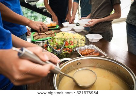 Volunteers Serving Food To Poor People In Charity Centre, Closeup