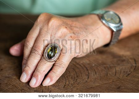 Senior Man Is Wearing Jewellery Ring In Left Ring Finger And Silver Watch On Wooden Background, Sebo