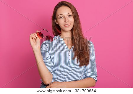 Close Up Portrait Of Woman Holding Glasses In Hands, Stands Smiling Isolated Over Pink Background, L