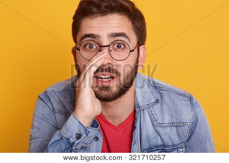 Horizontal Shot Of Handsome Man Wearing Casual Red T Shirt And Stylish Demin Jacket, Keeps Hand On M