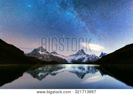Incredible night view of Bachalpsee lake in Swiss Alps mountains. Snowy peaks of Wetterhorn, Mittelhorn and Rosenhorn on background. Grindelwald valley, Switzerland. Landscape astrophotography