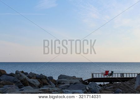 Red And Green Empty Camping Chairs On The Shore Of The Sea