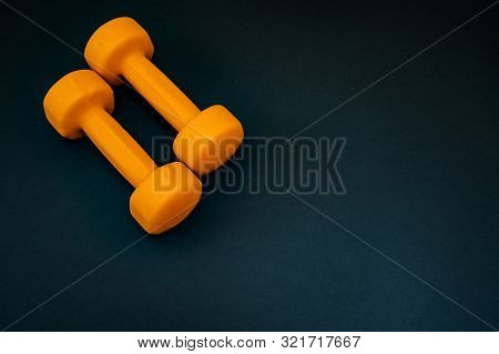 Two Orange Dumbbells Isolated On Black Background