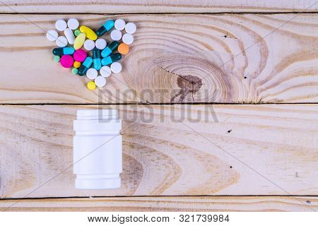 Assorted Pharmaceutical Medicine Pills, Tablets And Capsules And Bottle On Wooden Table Background.