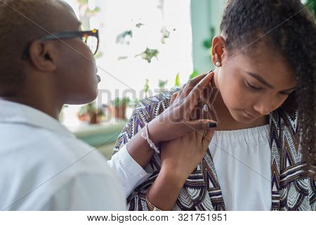 An African American Female Doctor Examines With Her Fingers, Palpates Her Neck And Lymph Nodes. Pain