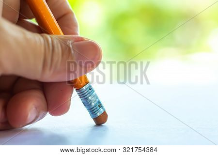 Woman's Left Hand Hold Orange Riangular Pencil, Rubber To Delete From White Paper, Bokeh Green Garde